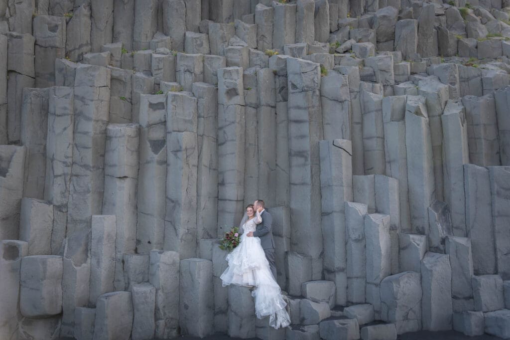 Wedding couple standing on the basalt columns at Reynisfjara in Iceland
