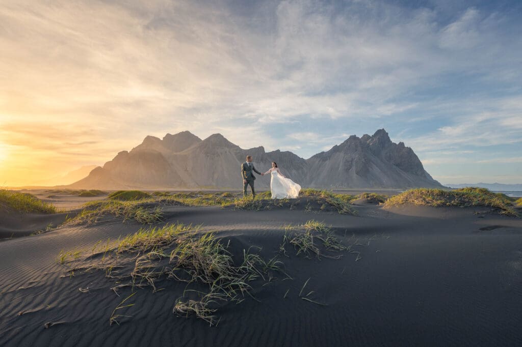 A couple in wedding attire with Vestrahorn mountain range in the background at golden hour