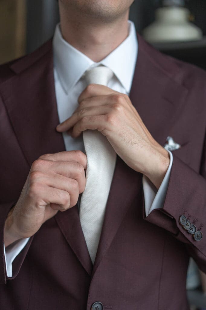Detail of a groom fixing his tie